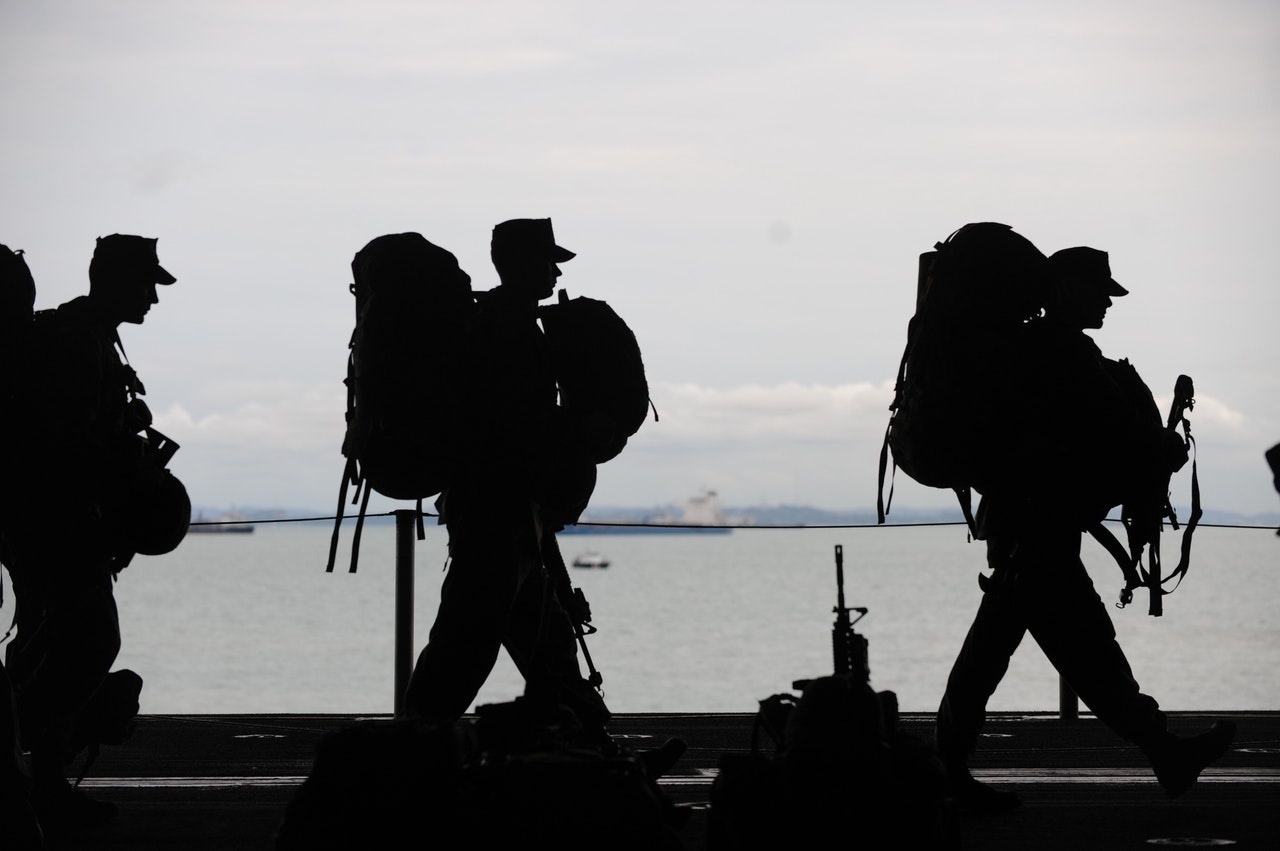 silhouette of soldiers carrying equipment