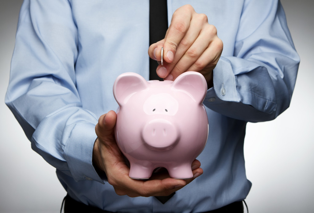 male hand saving money in a piggy bank