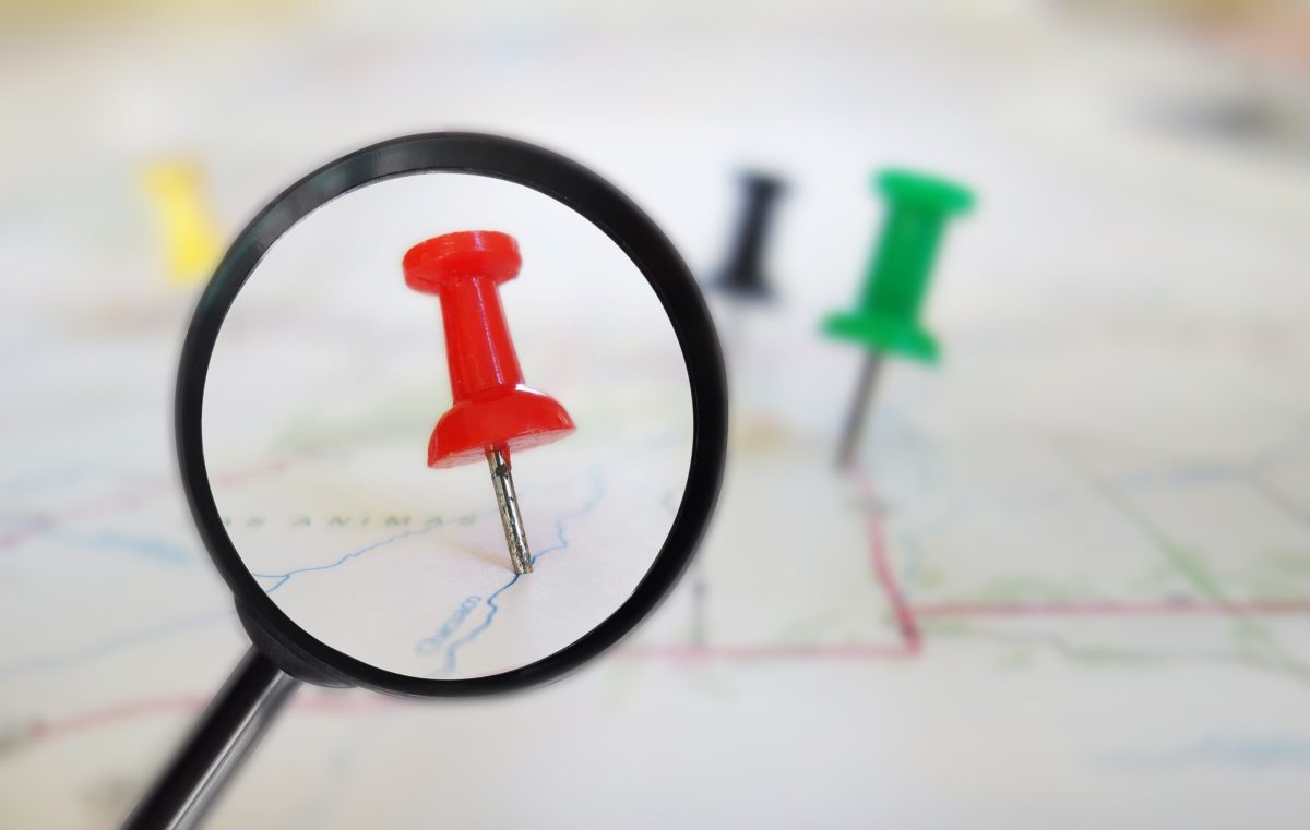 location in a map marked by red push pin under magnifier